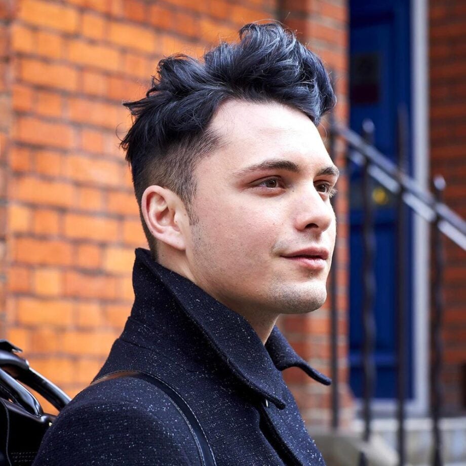 Man with stylish hairstyle in dark coat.