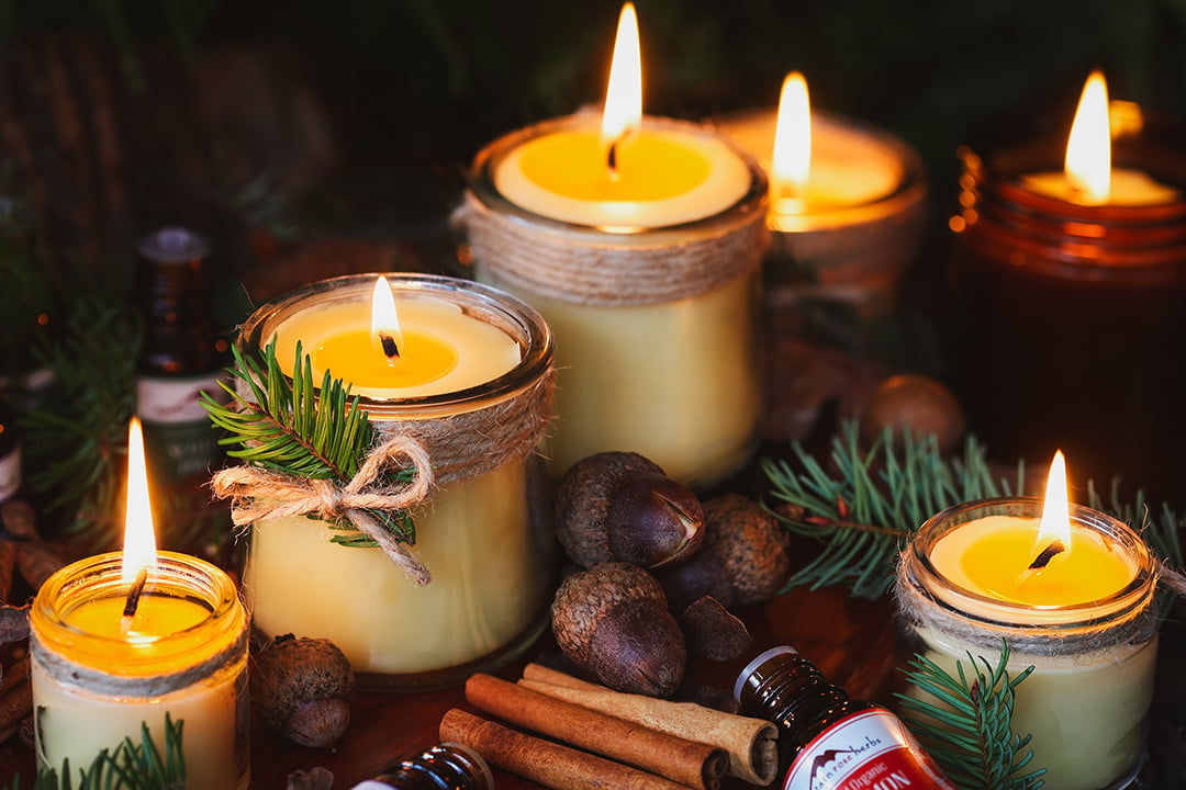 Lit homeamde candles with twine and fir tips in a warm and cozy setting. 