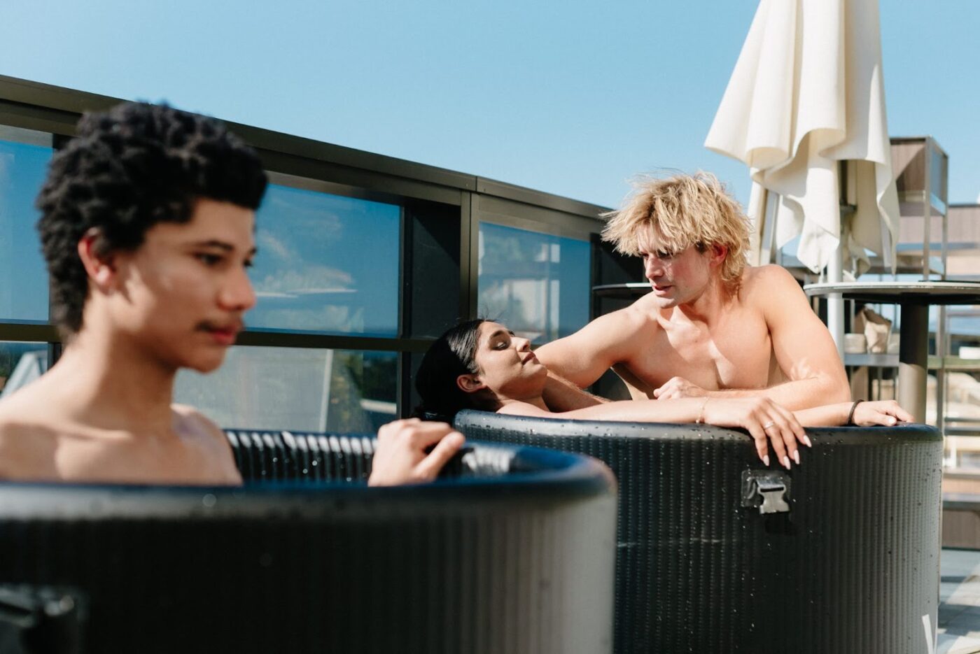 Three people in hot tubs.